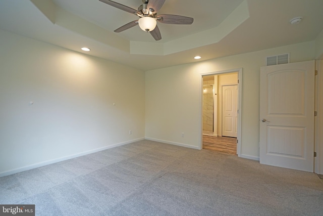 empty room with light carpet, baseboards, visible vents, a tray ceiling, and recessed lighting