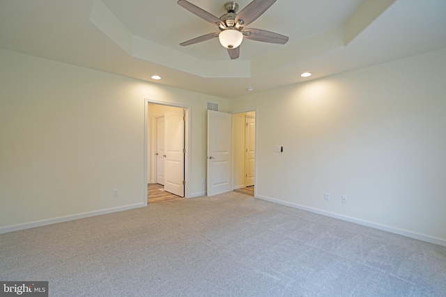 unfurnished bedroom featuring visible vents, baseboards, a raised ceiling, light colored carpet, and recessed lighting