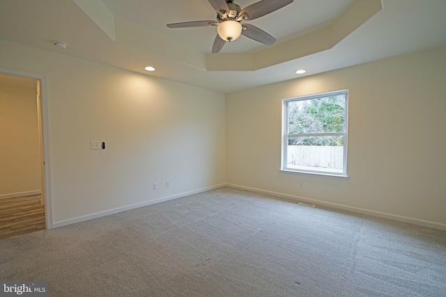 spare room with carpet floors, baseboards, a tray ceiling, and recessed lighting