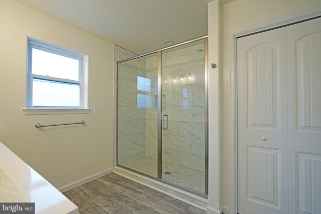 full bathroom with wood finished floors, a shower stall, and baseboards