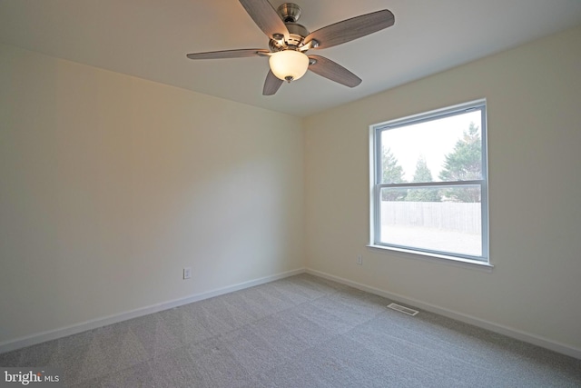 empty room with light carpet, a ceiling fan, visible vents, and baseboards