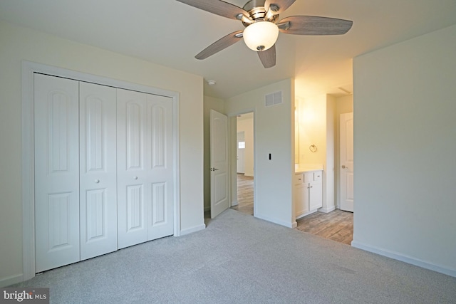 unfurnished bedroom with a closet, visible vents, light carpet, and baseboards