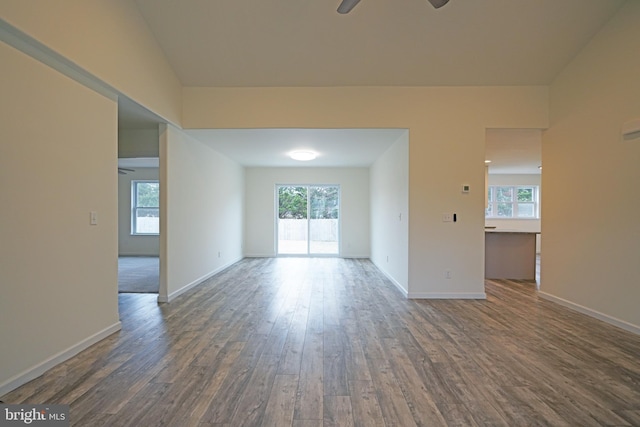 empty room featuring plenty of natural light, dark wood-style flooring, and a ceiling fan