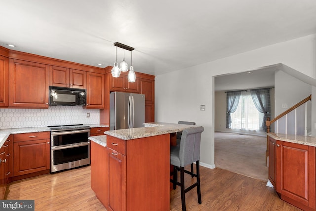 kitchen with light wood finished floors, a kitchen breakfast bar, stainless steel appliances, a kitchen island, and decorative backsplash