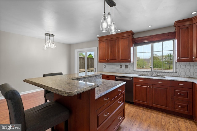 kitchen with a sink, backsplash, dishwasher, a breakfast bar area, and hanging light fixtures