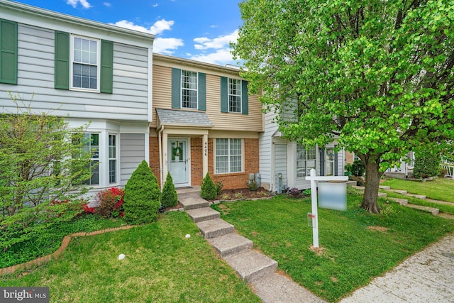 view of property featuring a front lawn and brick siding