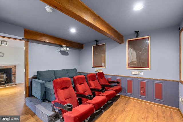 cinema room featuring recessed lighting, a brick fireplace, wood finished floors, and beam ceiling