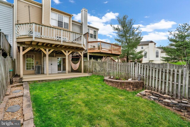 back of property with a fenced backyard, a wooden deck, and a yard