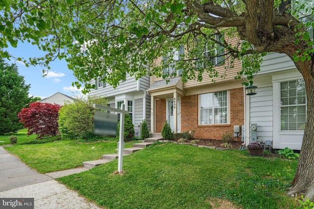 multi unit property with a front lawn and brick siding