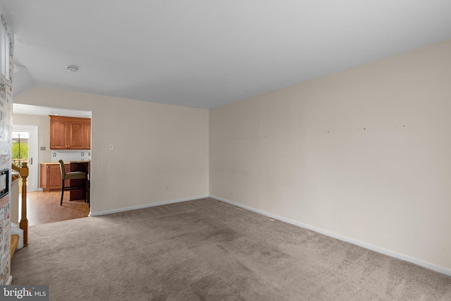 spare room featuring vaulted ceiling, baseboards, and light colored carpet