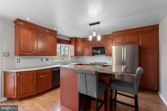 kitchen with backsplash, light wood finished floors, and appliances with stainless steel finishes