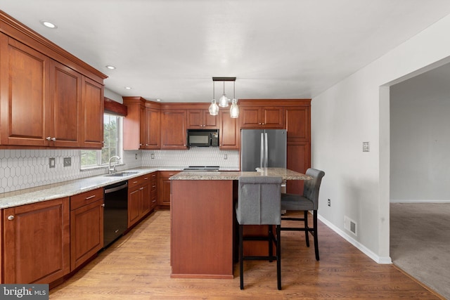 kitchen with black microwave, dishwasher, a kitchen bar, visible vents, and freestanding refrigerator