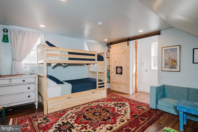 bedroom featuring hardwood / wood-style flooring, a barn door, and lofted ceiling