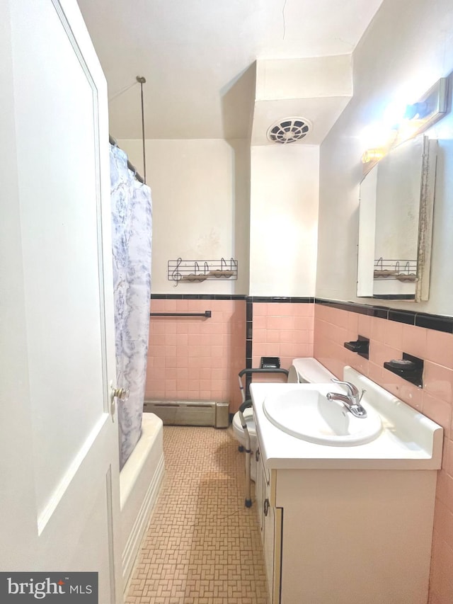 full bathroom with tile walls, vanity, tile patterned flooring, toilet, and baseboard heating