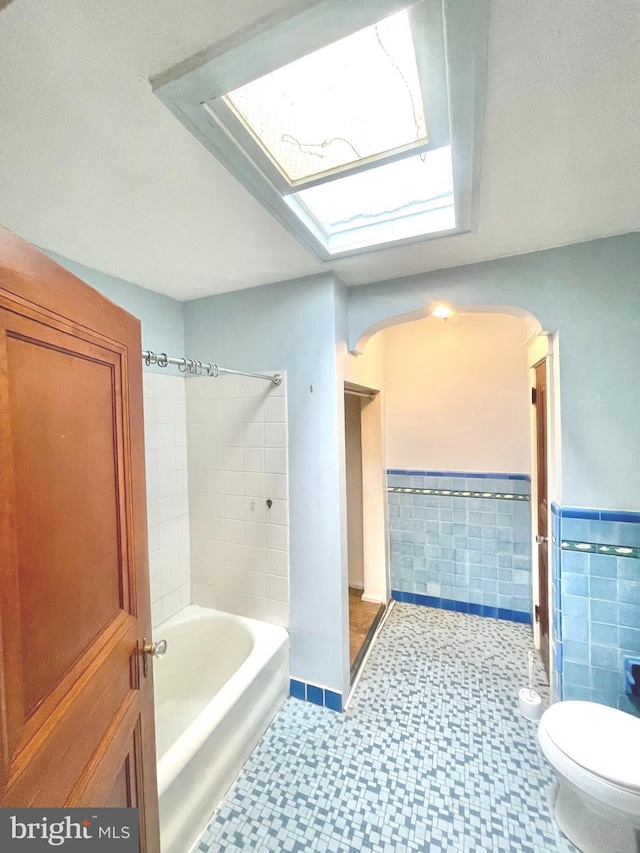 bathroom with shower / tub combination, tile walls, and toilet