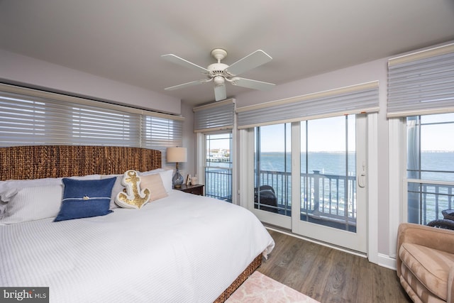 bedroom with multiple windows, access to exterior, hardwood / wood-style flooring, and a water view