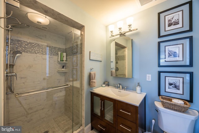 bathroom featuring vanity, toilet, and a shower with shower door