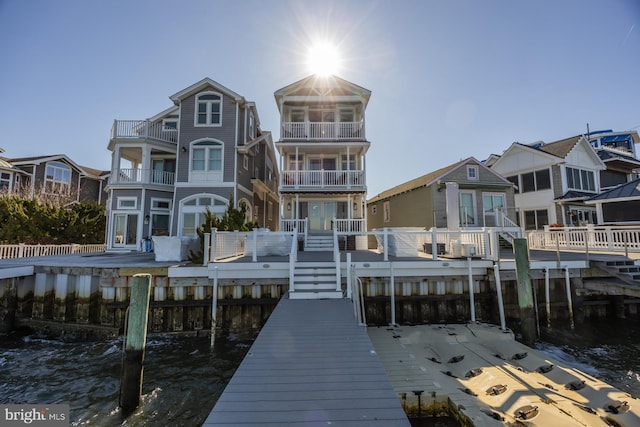 rear view of house with a balcony and a deck with water view