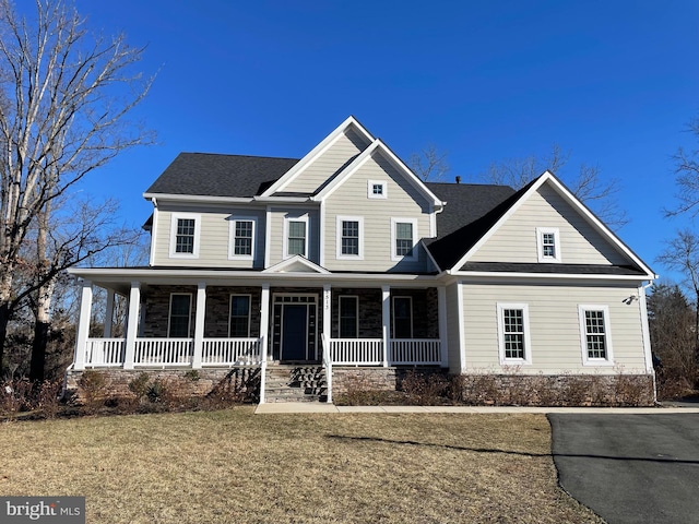 view of front of house featuring covered porch, roof with shingles, and a front yard