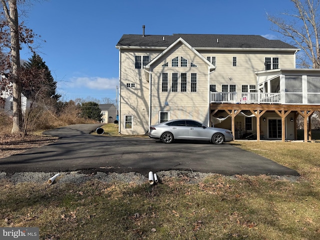 rear view of house featuring a yard and a sunroom