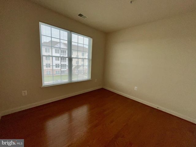 unfurnished room featuring visible vents, baseboards, and dark wood-type flooring