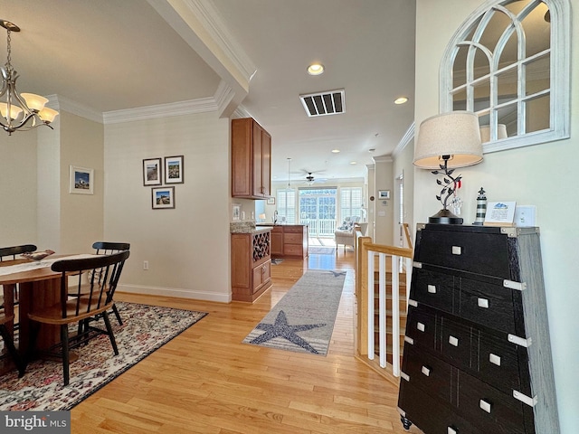 dining room featuring crown molding, light wood-style flooring, baseboards, and visible vents