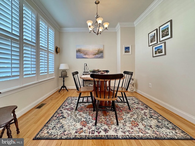 dining area with visible vents, baseboards, ornamental molding, wood finished floors, and a notable chandelier