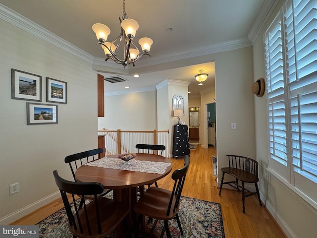 dining room with visible vents, light wood-style floors, an inviting chandelier, crown molding, and baseboards