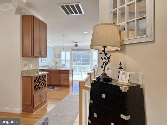 hall with light wood finished floors, visible vents, crown molding, baseboards, and recessed lighting