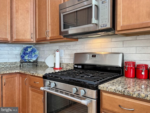 kitchen with light stone counters, stainless steel appliances, tasteful backsplash, and brown cabinetry