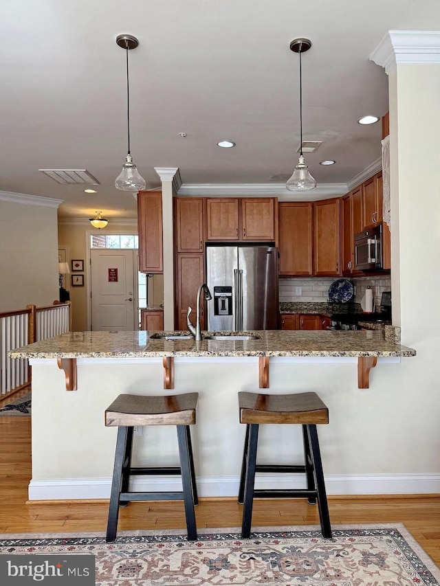 kitchen featuring light stone countertops, stainless steel appliances, crown molding, and a sink