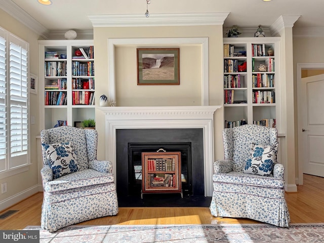 living area featuring a fireplace with flush hearth, wood finished floors, visible vents, and ornamental molding