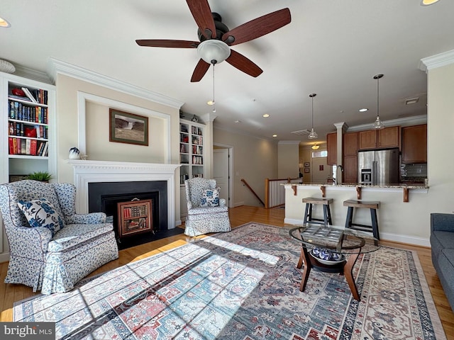 living room with light wood-style flooring, crown molding, and a ceiling fan