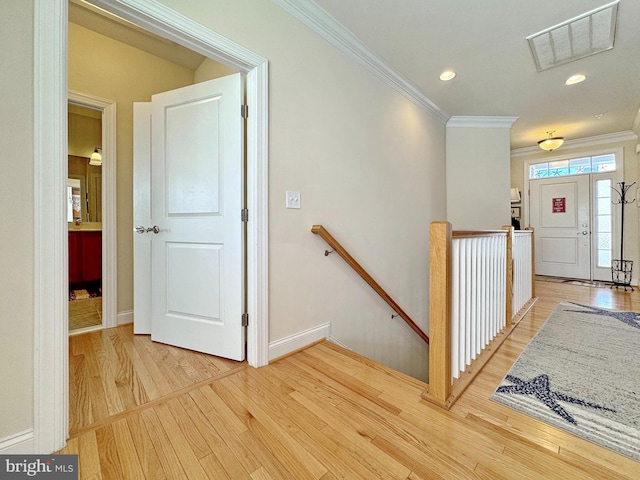 corridor with baseboards, visible vents, crown molding, an upstairs landing, and light wood-type flooring