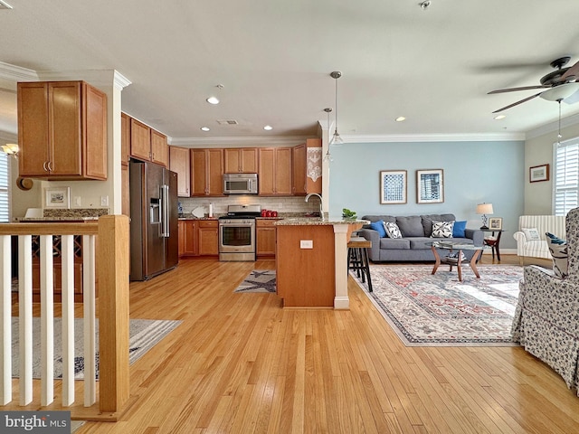 kitchen with open floor plan, a peninsula, appliances with stainless steel finishes, crown molding, and ceiling fan