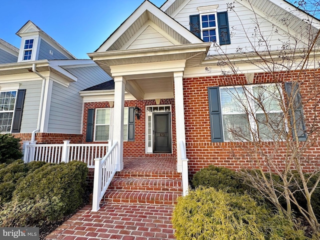 entrance to property featuring brick siding and covered porch