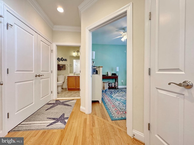 corridor featuring light wood-style flooring, recessed lighting, baseboards, and ornamental molding