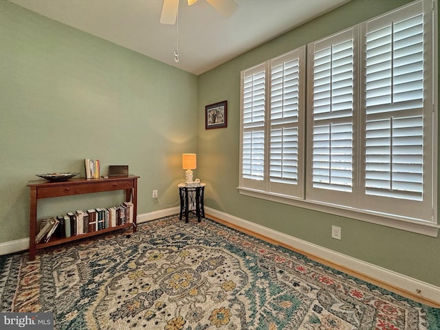 sitting room featuring a ceiling fan and baseboards