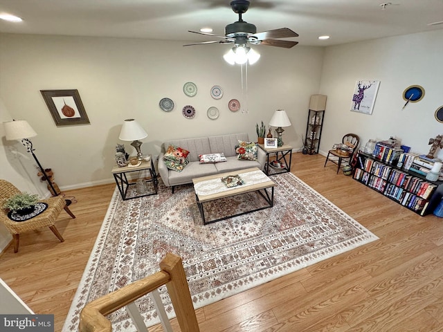 living area featuring baseboards, ceiling fan, and wood finished floors