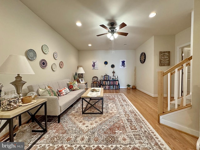 living room with baseboards, stairs, a ceiling fan, and wood finished floors