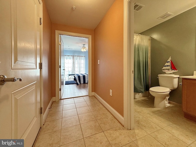 hallway featuring light tile patterned floors, visible vents, and baseboards