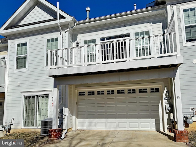 rear view of house featuring cooling unit, driveway, an attached garage, and a balcony