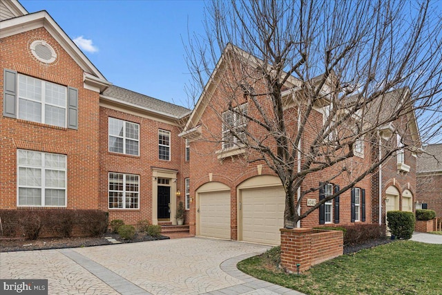 view of front of home featuring decorative driveway, brick siding, a garage, and a shingled roof