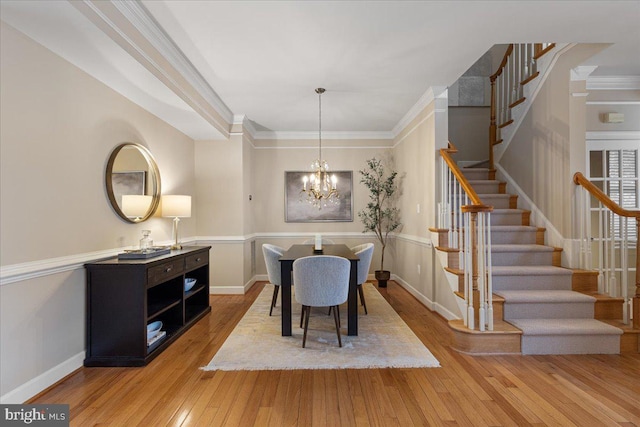 dining space with light wood finished floors, crown molding, baseboards, stairs, and an inviting chandelier