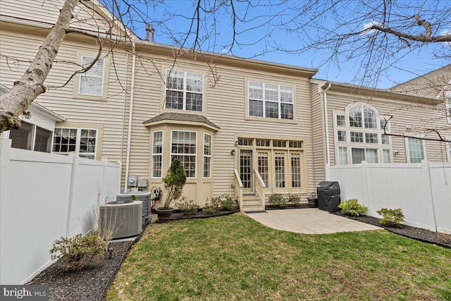 back of house featuring a lawn, central AC unit, entry steps, and fence