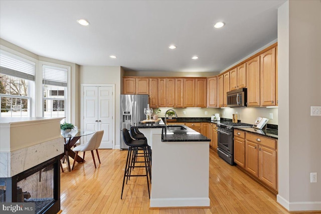 kitchen with a breakfast bar area, recessed lighting, light wood-style floors, stainless steel appliances, and a sink