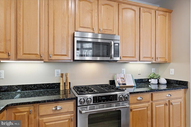 kitchen with dark stone countertops, light brown cabinetry, and stainless steel appliances