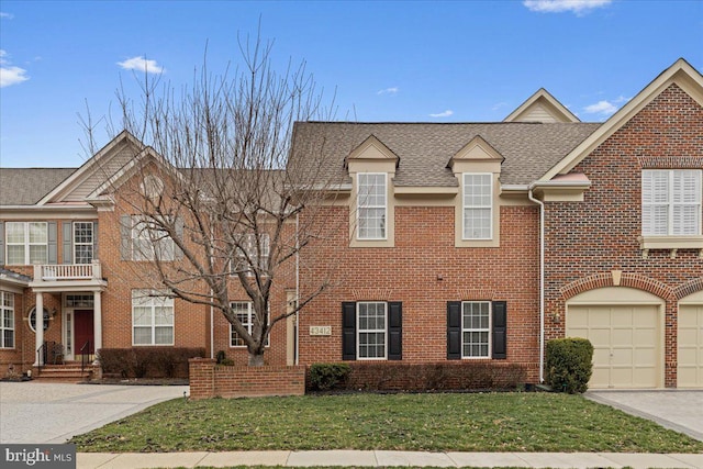 view of front facade with brick siding, driveway, a shingled roof, and a front yard