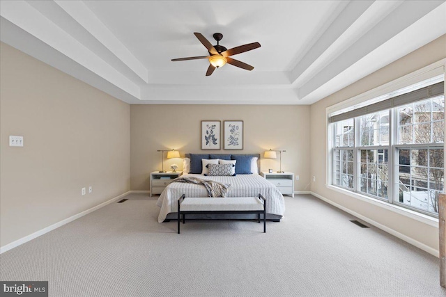 bedroom featuring a tray ceiling, baseboards, visible vents, and carpet floors