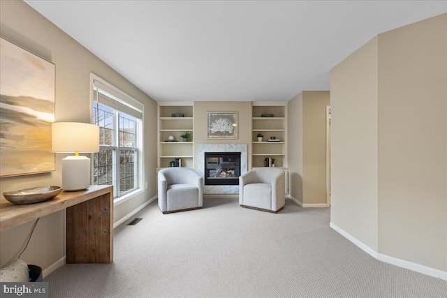 unfurnished room featuring built in shelves, visible vents, baseboards, carpet floors, and a fireplace